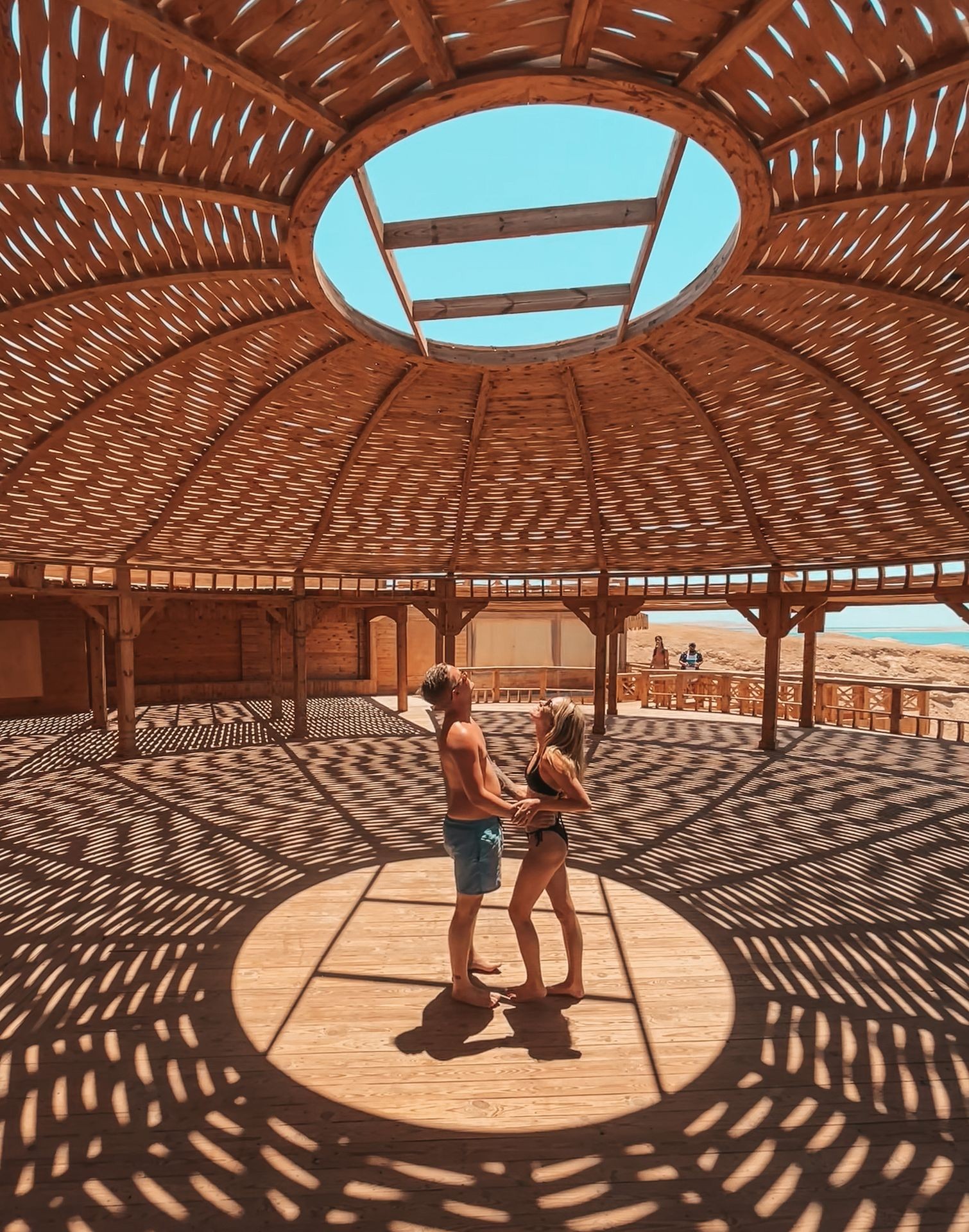 Ein atemberaubender Fotospot auf Orange Bay: Ein Paar genießt die Aussicht unter einer traditionellen Strohhütte mit kunstvollen Lichtmustern. Orange Bay Hurghada ist bekannt für seine malerischen Instagram-Spots, weißen Sandstrände und Luxus-Ausflüge mit dem Boot – ideal für Sonnenanbeter und Fotografen.