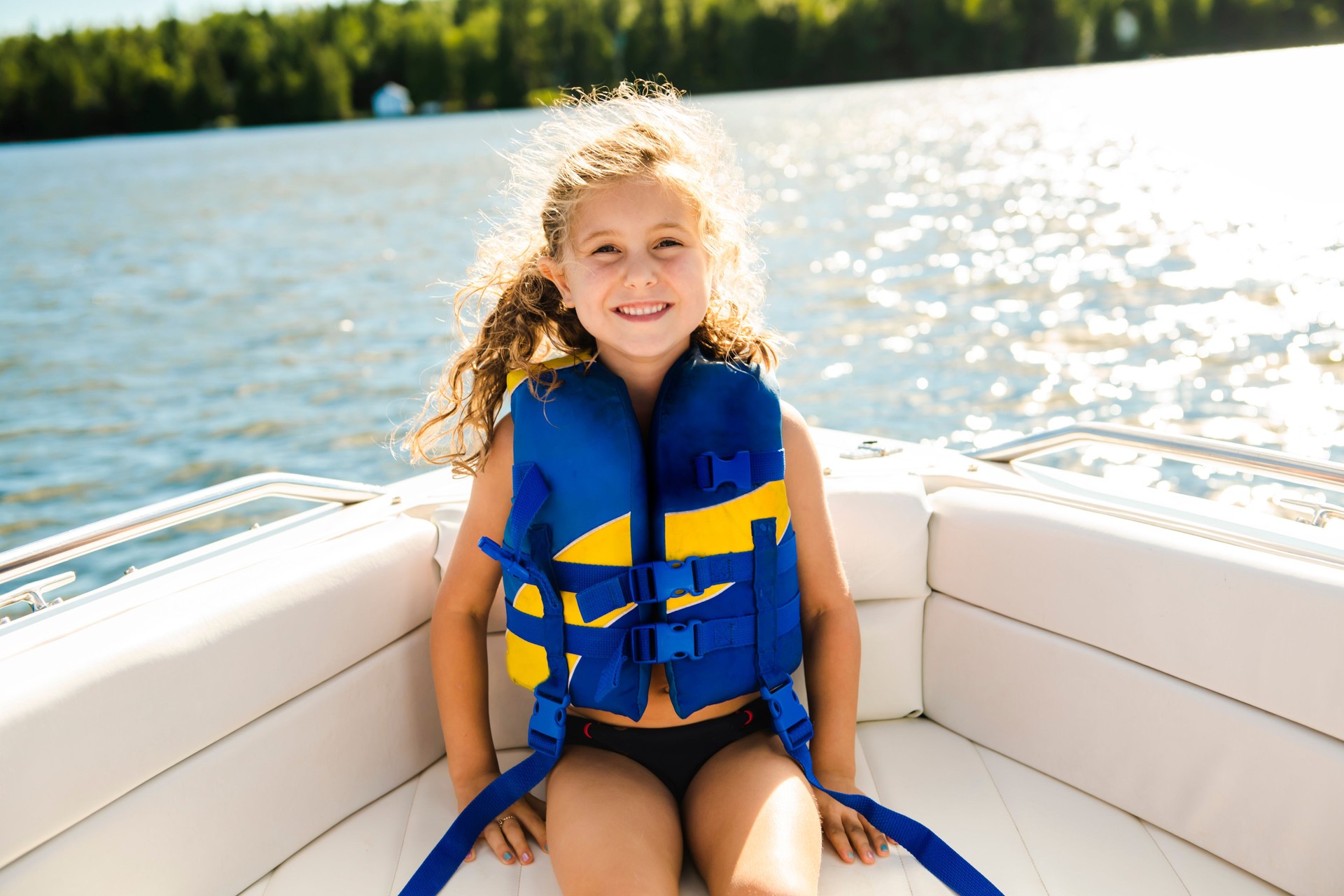 child with safety vest on the lake boat