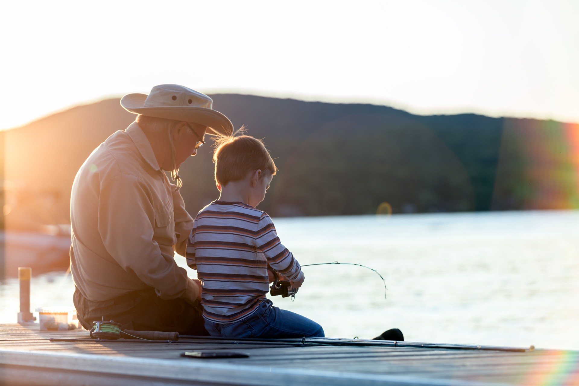 Grandfather and Grandson Fishing At Sunset in Summer