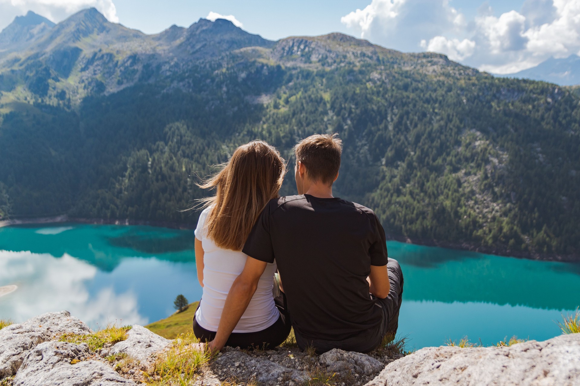 junges Paar in Liebe auf einem Felsen sitzen und bewundern Sie die schöne Aussicht in den Schweizer Alpen