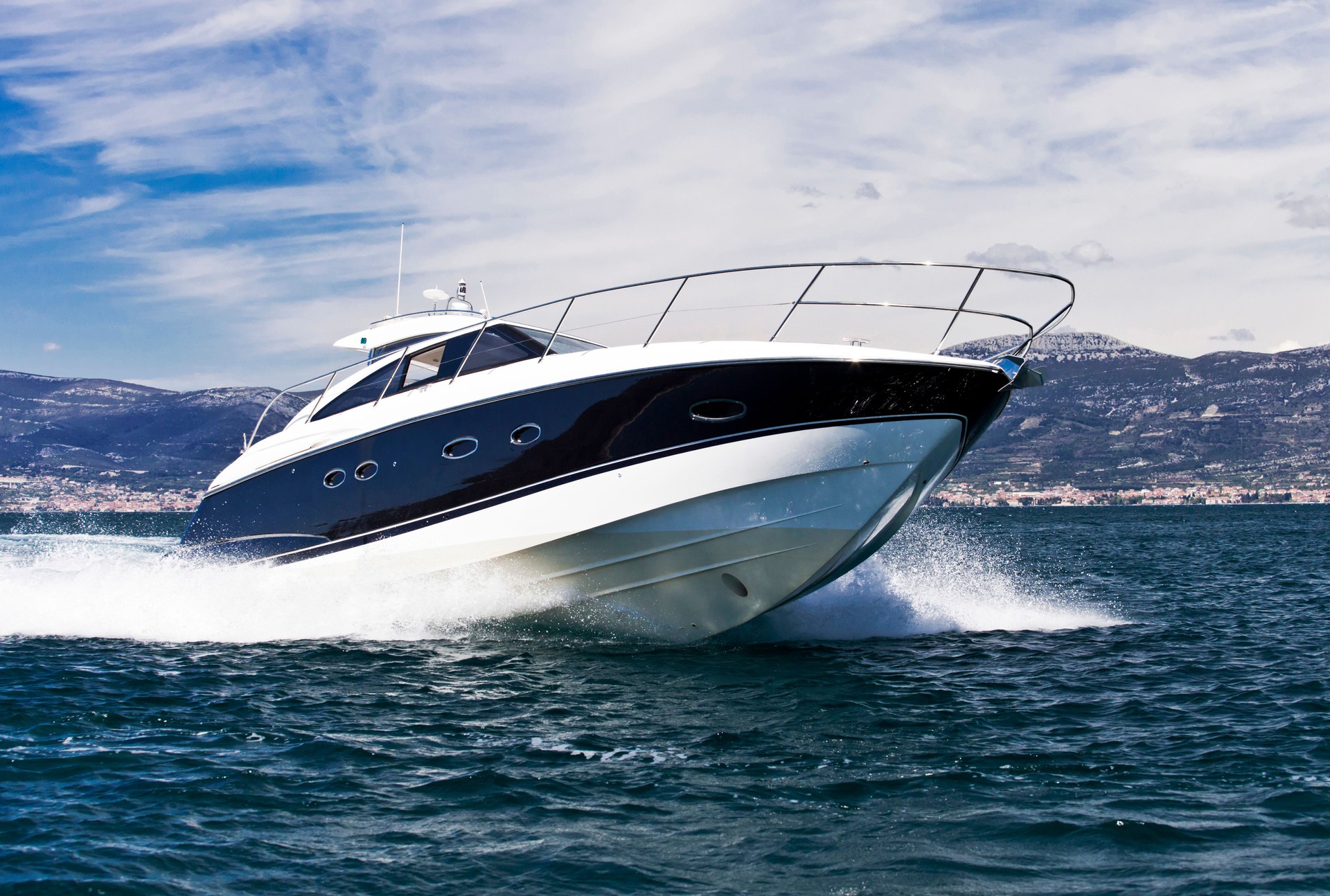 A blue striped white yacht speeding across the sea