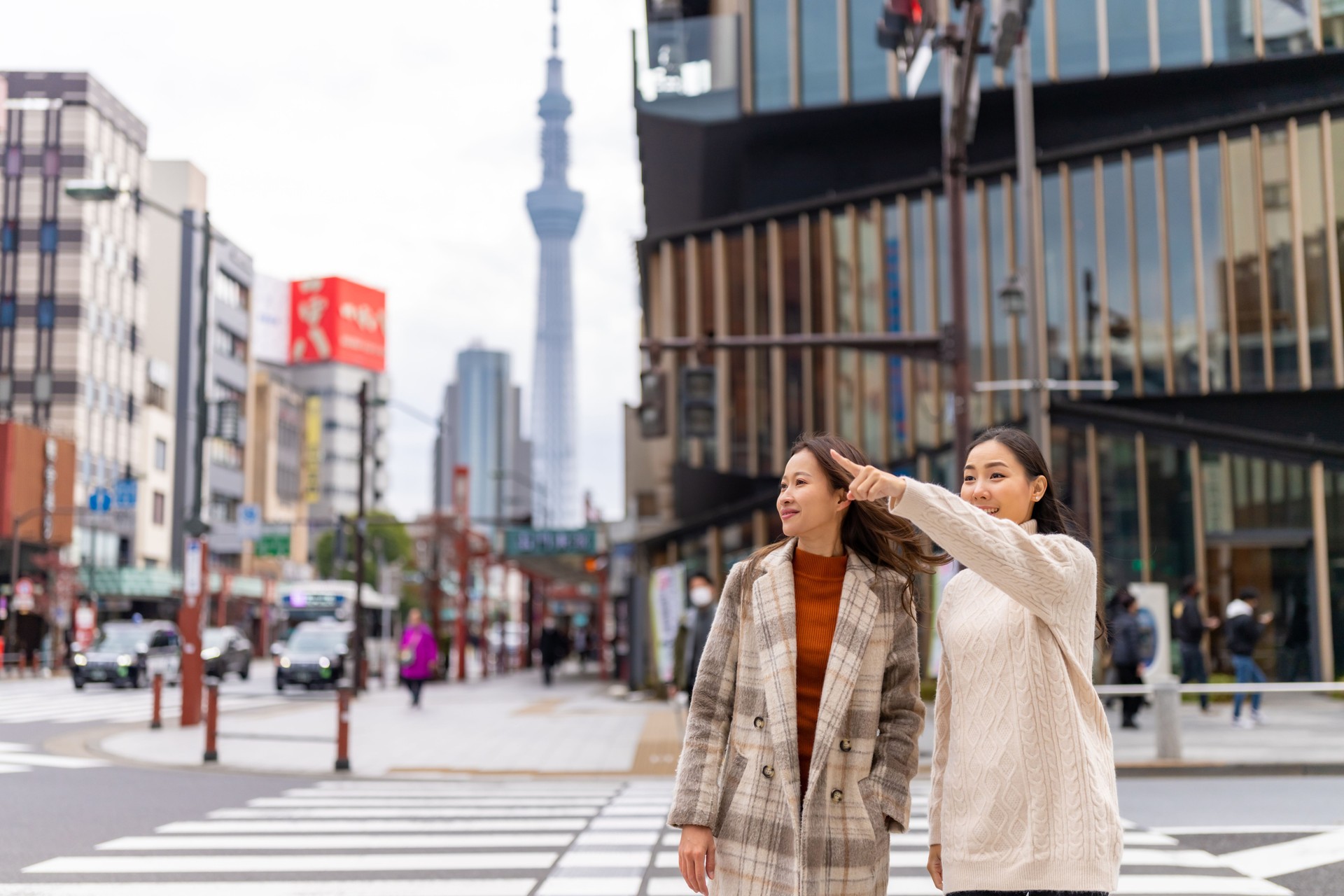 asiatische fraufreunde, die den zebrastreifen in der stadt toto, japan, überqueren.