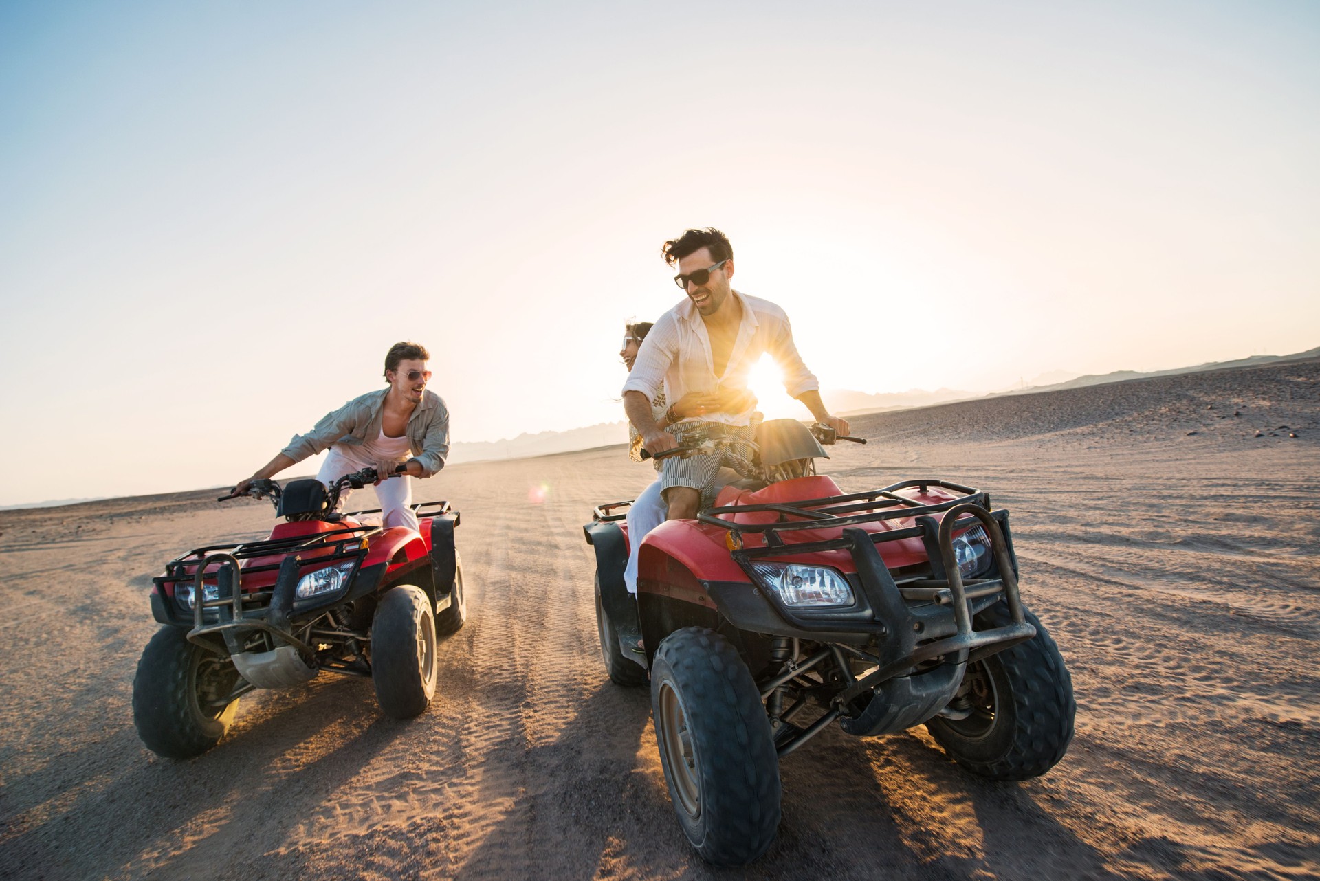 Playful people on quad bikes in the desert.